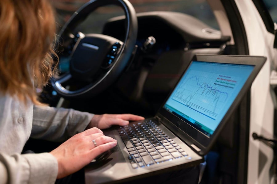 woman laptop with code on screen at a car